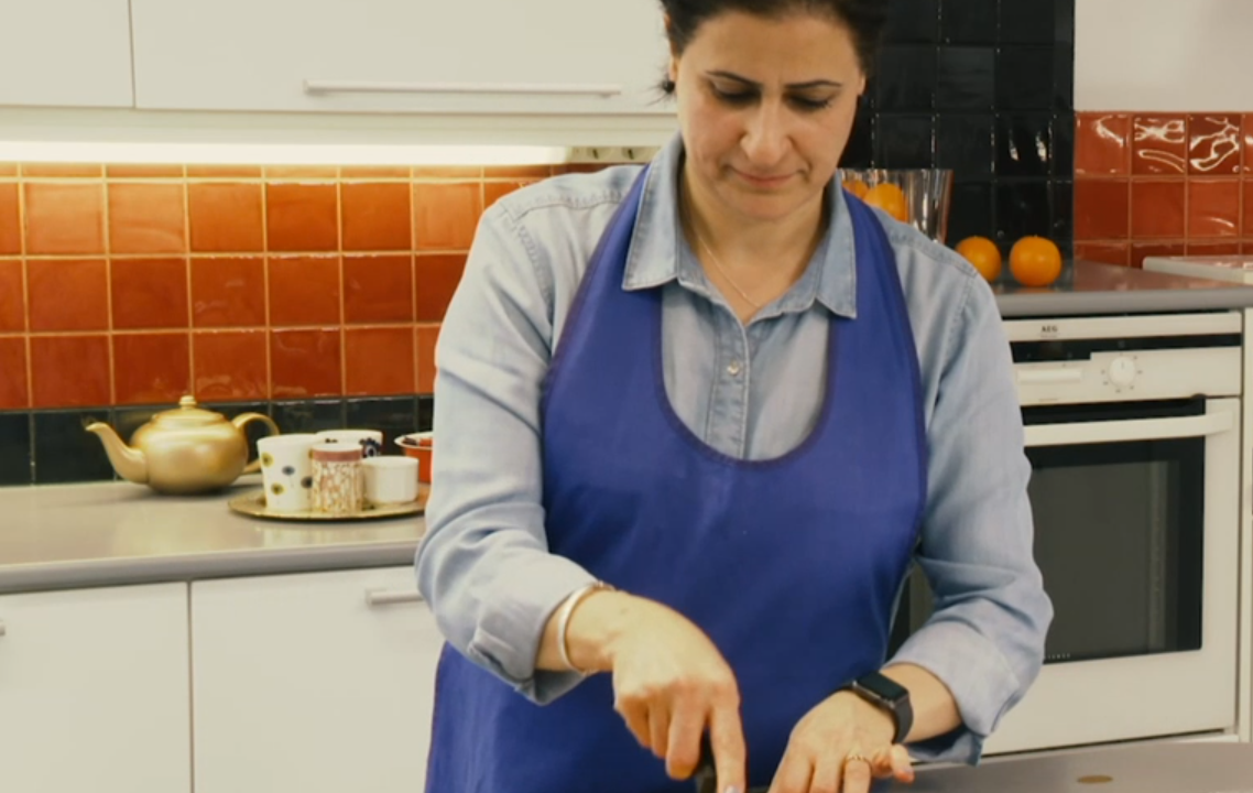 Nainen seisoo keittiössä ja leikkaa aprikoosipiirakkaa